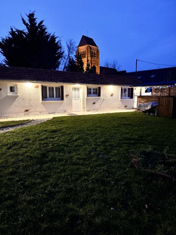 une maison blanche avec une tour d'horloge en arrière-plan dans l'établissement Maison individuelle aux portes de la Sologne, à La Ferté-Saint-Aubin