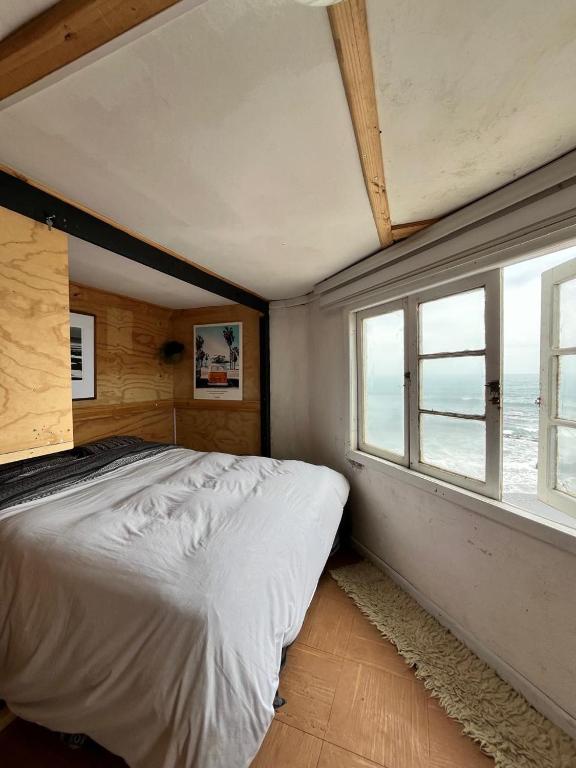 um quarto com uma cama grande e uma janela em El Barco Pichilemu em Pichilemu