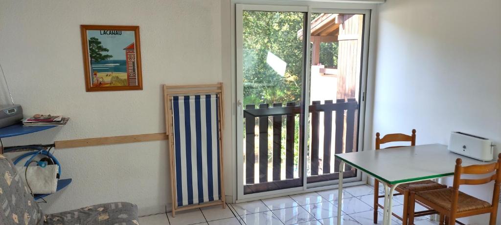 a living room with a table and a balcony at Petit Appartement dans les Arbres in Carcans