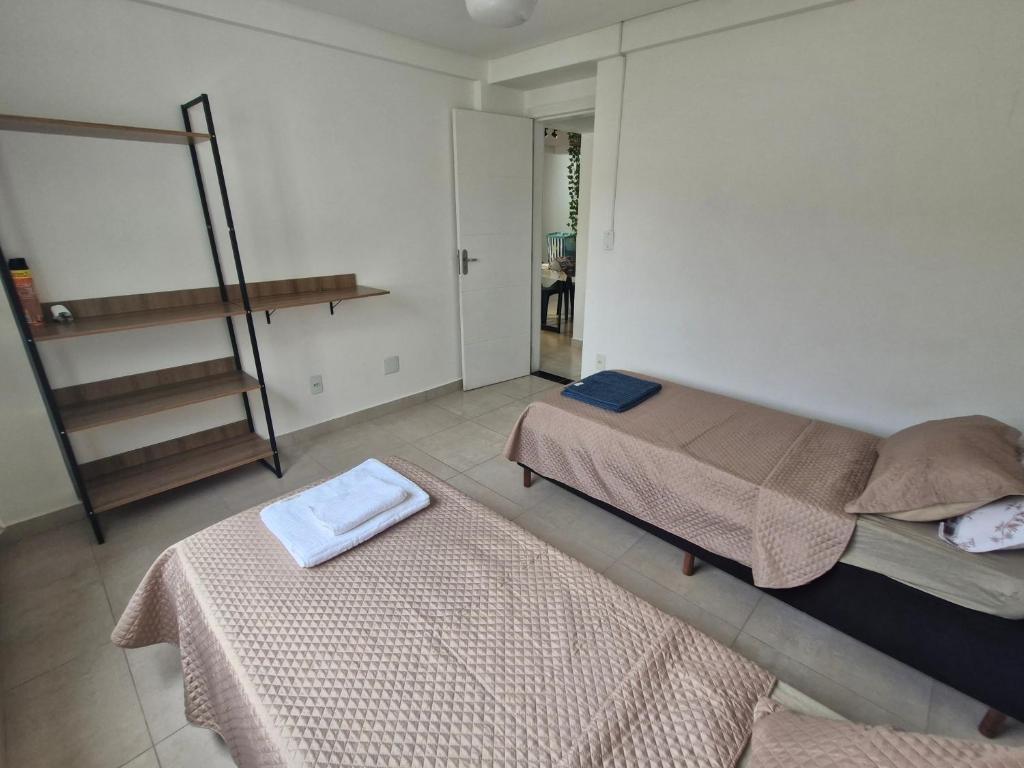 a bedroom with two beds and a shelf with towels at Apto no Caminho das Praias in Balneário Camboriú