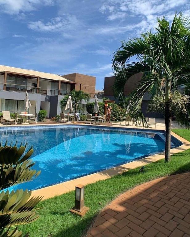 a swimming pool with a palm tree next to a building at Conforto e Paz in Imbassai