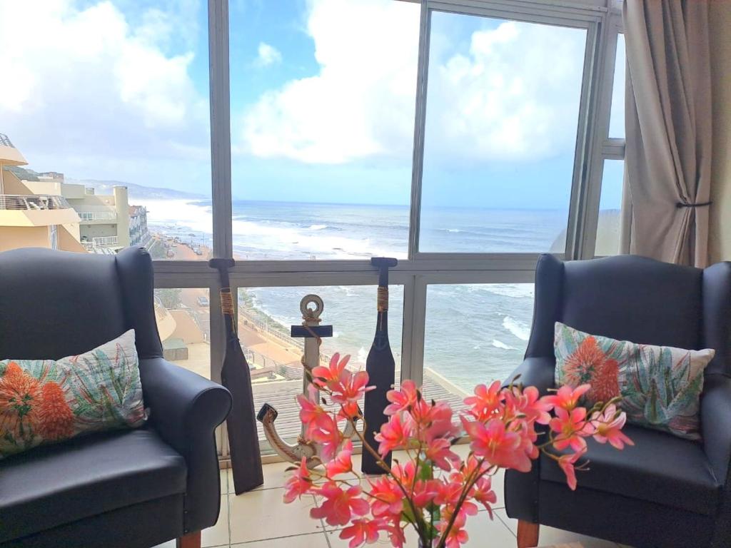 two chairs and a vase with flowers in front of a window at Ocean Tides - 2 Adults & 4 Kids ONLY in Umdloti