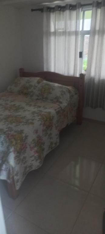 een slaapkamer met een bed met een bloemendeken en een raam bij Espaço tranquilo in Florianópolis