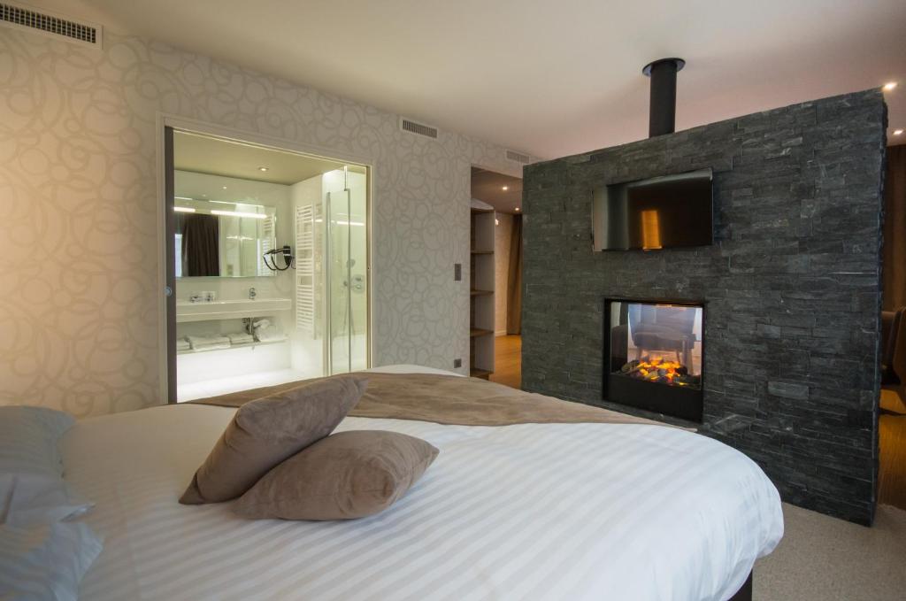 a bedroom with a large bed with a fireplace at Brit Hotel & Spa Saint Brieuc Plérin in Plérin