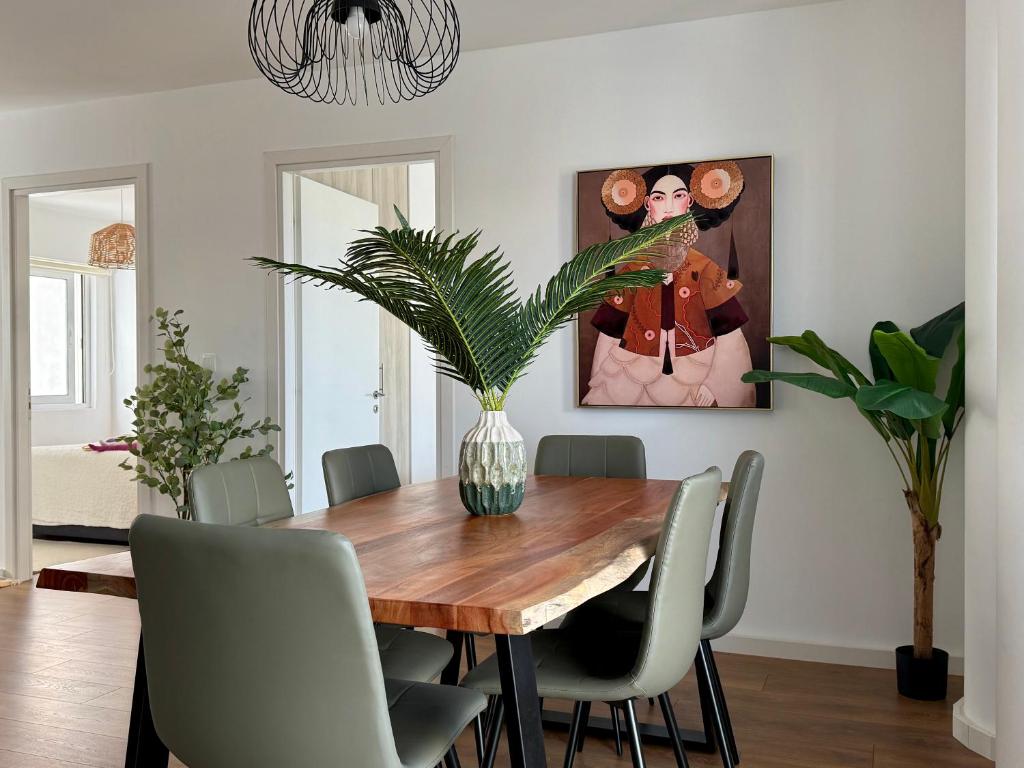 a dining room with a wooden table and a vase with a plant at TH0 Luxury two bedrooms Apartments with High-Tech Amenities in Athens