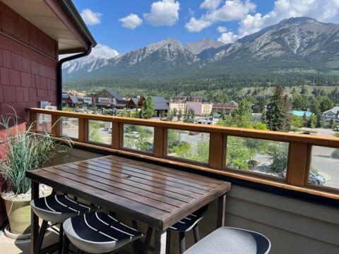 a wooden table and chairs on a balcony with mountains at Mountain Vista Escape Downtown in Canmore