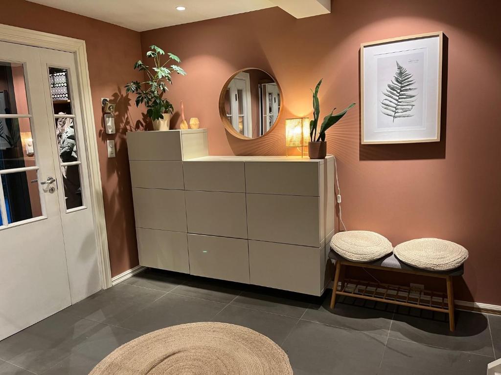 ein Badezimmer mit einem Spiegel und einer Kommode mit zwei Hockern in der Unterkunft Enebolig til utleie in Trondheim