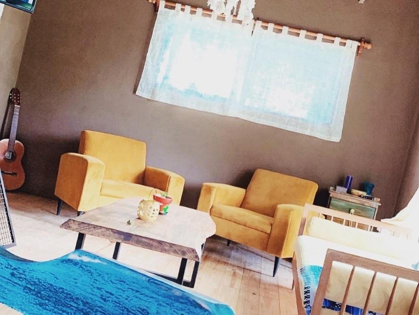 a living room with chairs and a table and a guitar at Casa de Mar y Barro in Maldonado