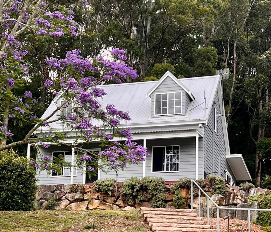 ein weißes Haus mit einem Baum mit lila Blumen in der Unterkunft Cottage Hill Creek near the beach and bush in Macmasters Beach
