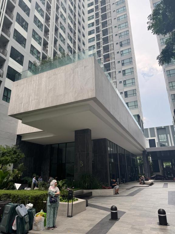 a woman is standing in front of a building at 芭提雅市中心The Base 高端公寓酒店 in Pattaya