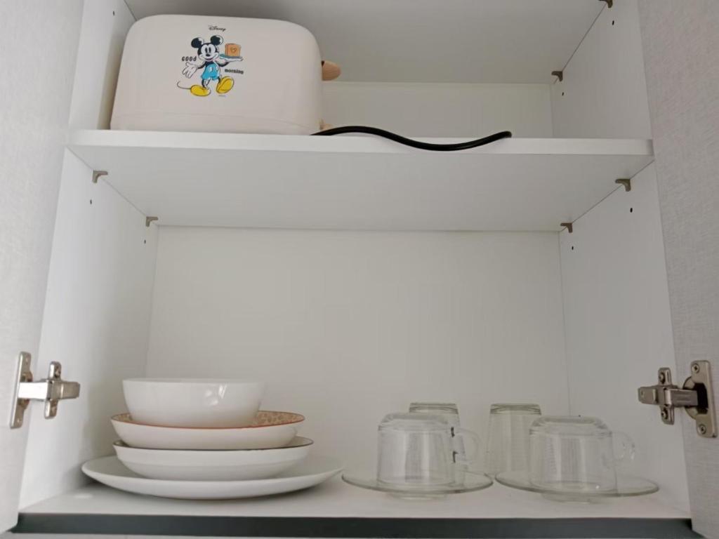 a kitchen shelf with dishes and a white appliance at 芭提雅市中心The Base 高端公寓酒店 in Pattaya