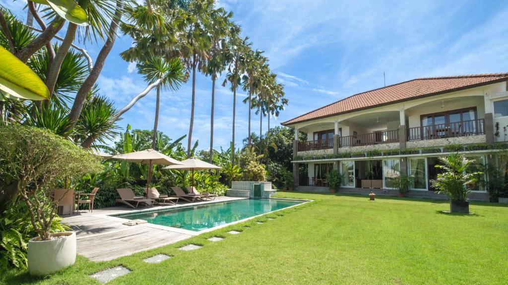 a villa with a swimming pool and palm trees at Villa Yenian by Villa Finder in Canggu