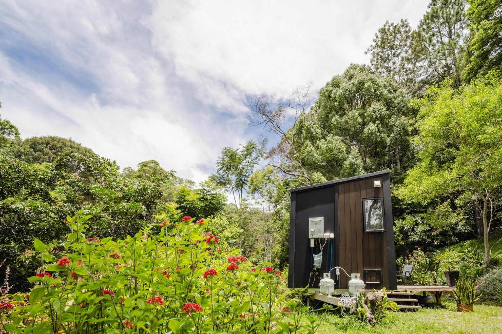 a tiny house in a garden with a bench at Secret Garden by Tiny Away in Uki