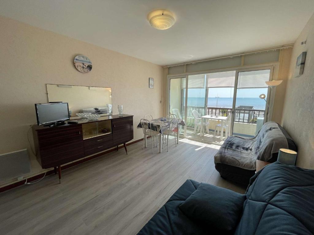 un salon avec un canapé et une télévision et un balcon dans l'établissement Studio en bord de mer avec balcon et parking - FR-1-224C-334, à Saint-Jean-de-Monts