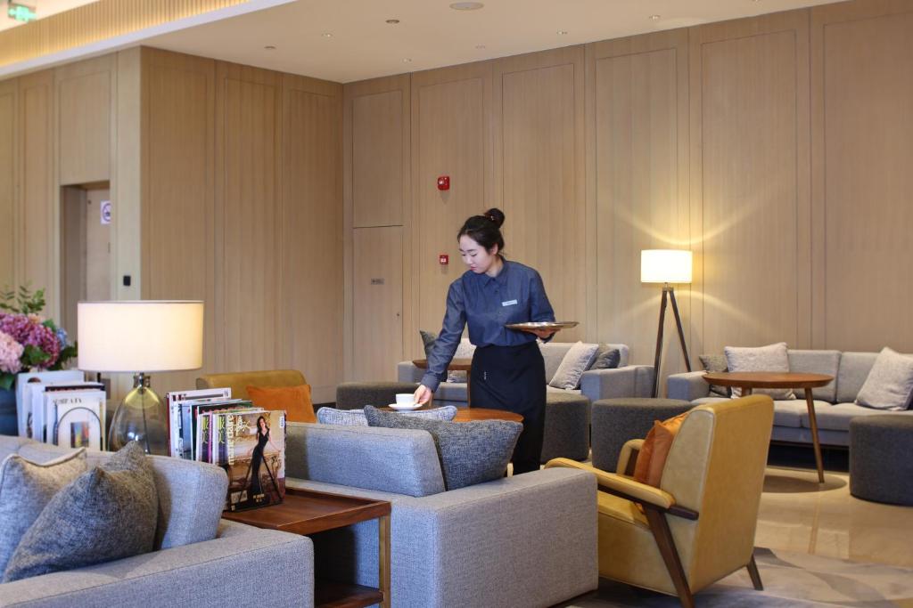 a woman standing in a room with couches at Hyatt House Shanghai Hongqiao CBD in Shanghai
