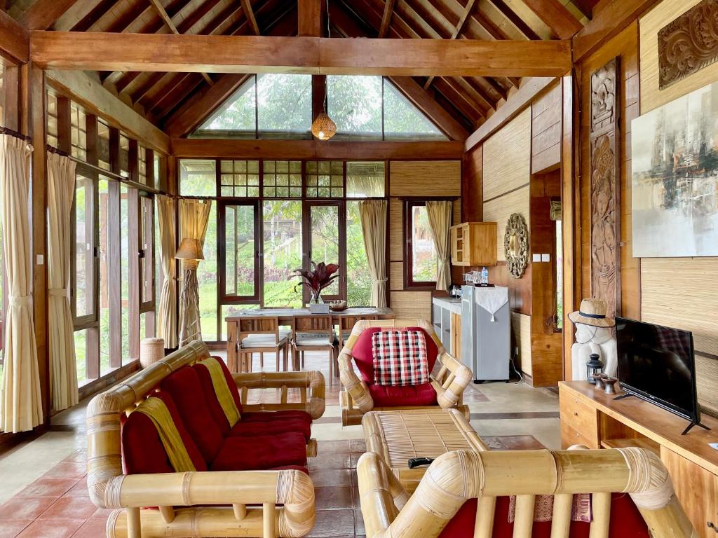 ein Wohnzimmer mit Stühlen und einem TV in einem Haus in der Unterkunft Sang Tirta Resort in Penebel