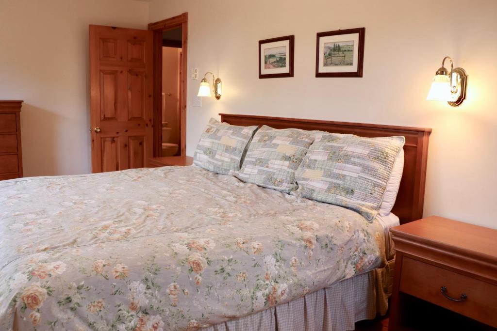 a bedroom with a bed with a floral bedspread at Shining Waters - Ingleside Cottages in Cavendish
