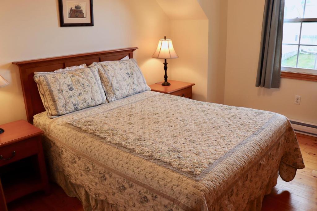 a bedroom with a bed and a lamp and a window at Shining Waters - Ingleside Cottages in Cavendish