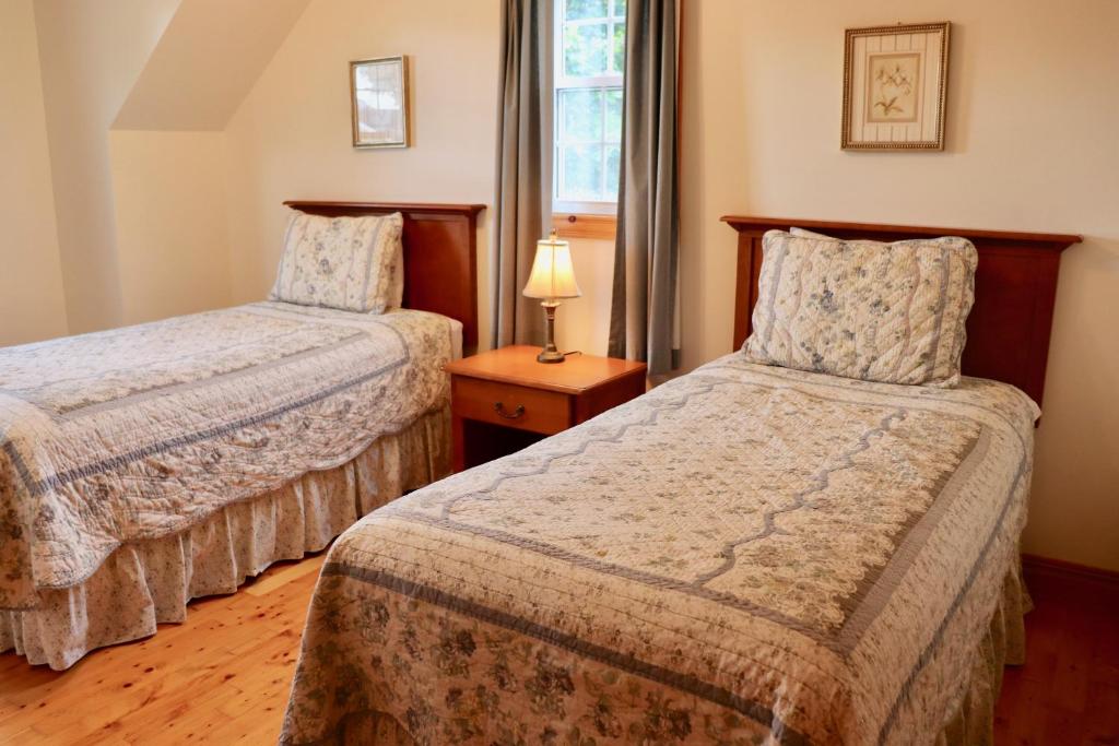 a bedroom with two beds and a lamp on a table at Shining Waters - Ingleside Cottages in Cavendish