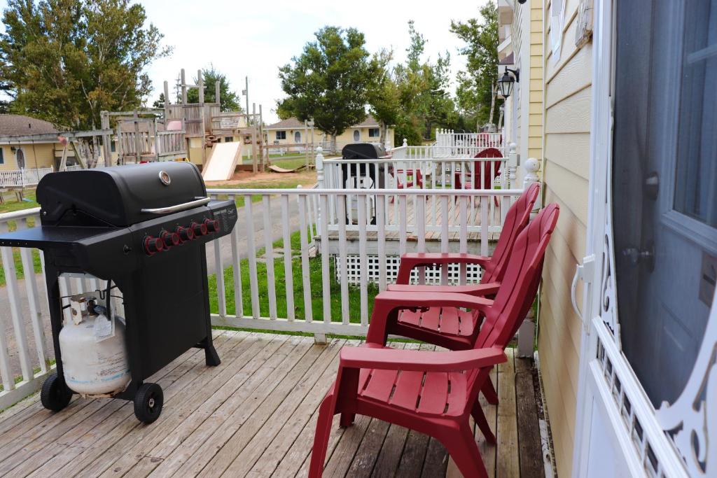 two red chairs and a grill on a porch at Shining Waters - Ingleside Cottages in Cavendish