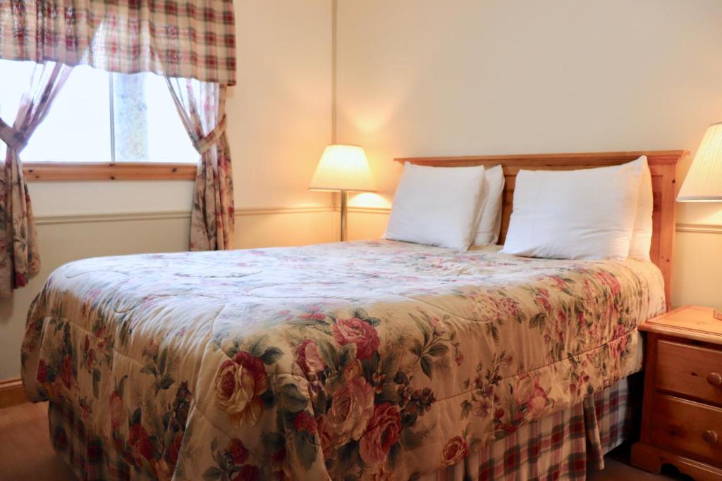 a bedroom with a bed with a floral bedspread at Shining Waters - Ingleside Cottages in Cavendish