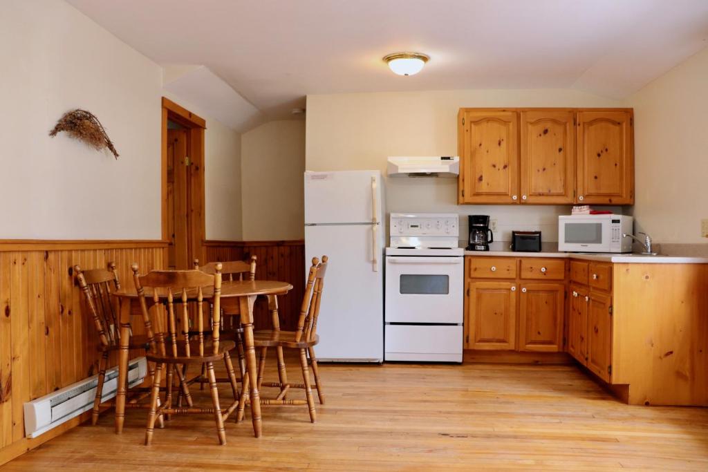 a kitchen with a table and a white refrigerator at Shining Waters - Ingleside Cottages in Cavendish