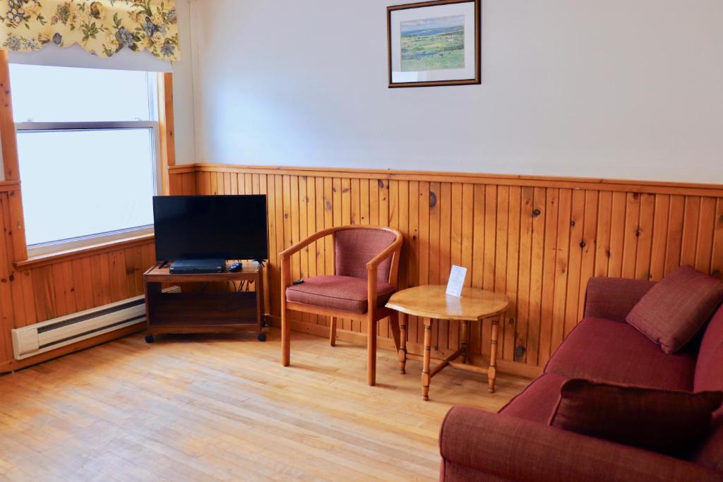 a living room with a couch and a chair and a tv at Shining Waters - Ingleside Cottages in Cavendish