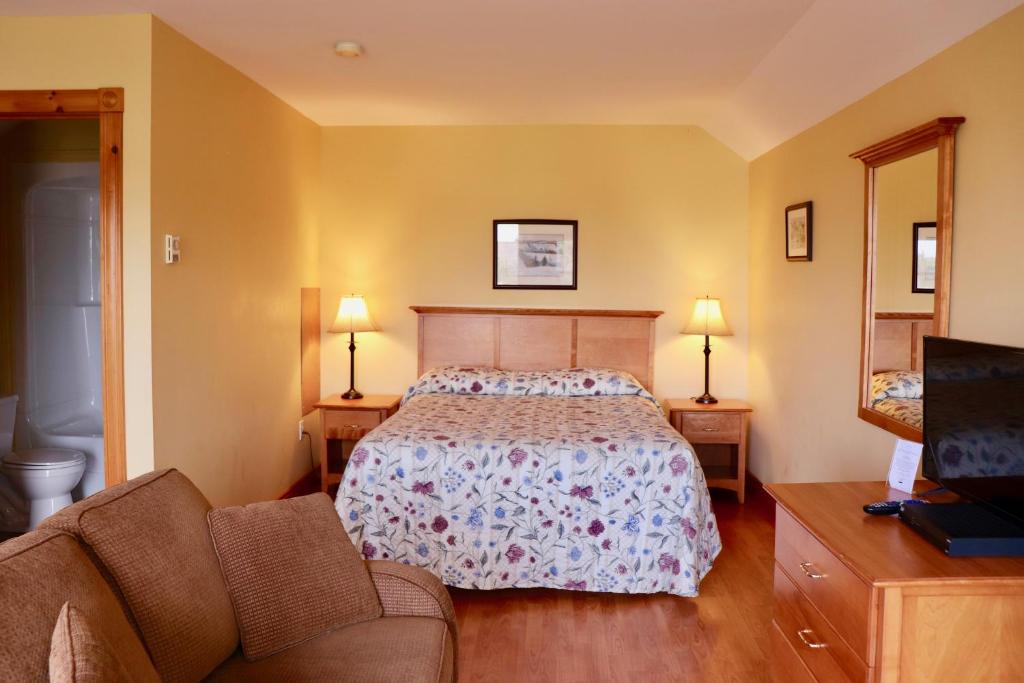 a bedroom with a bed and a couch and a television at Shining Waters - Ingleside Cottages in Cavendish