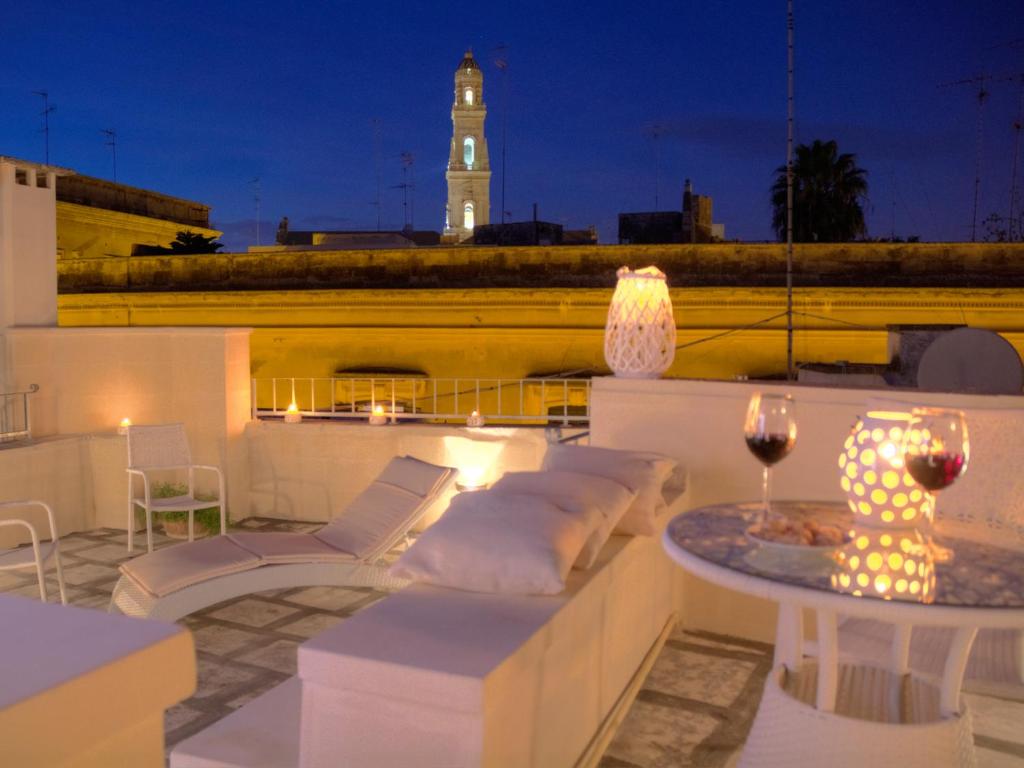 einen Balkon mit einem Tisch und Stühlen sowie einem Uhrturm in der Unterkunft B&B Corte dell' Idume in Lecce