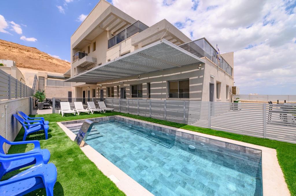 a house with a swimming pool and blue chairs at וילה מינרל villa mineral in Neve Zohar