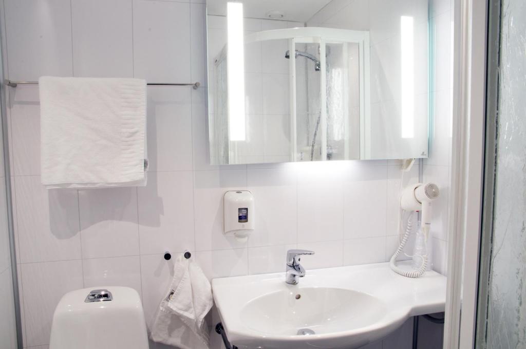 a white bathroom with a sink and a toilet at Hamarøy Hotel in Innhavet