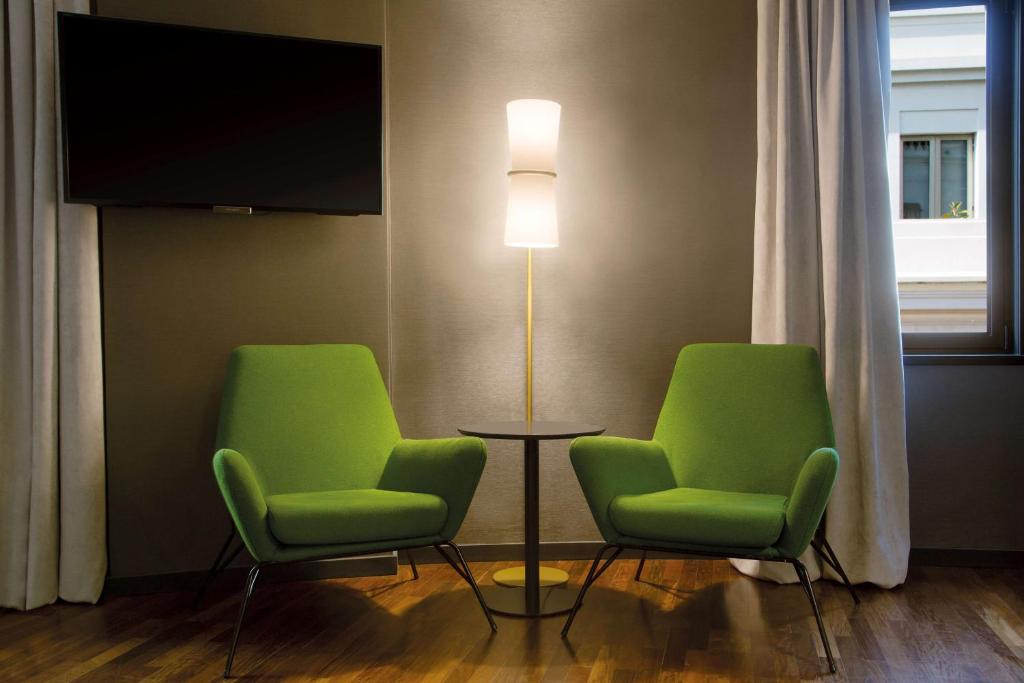 two green chairs and a floor lamp in a room at NH Collection Buenos Aires Jousten in Buenos Aires