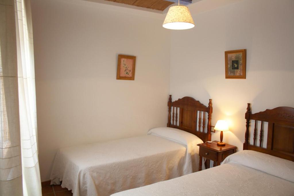 Casa Plana في Colungo: غرفة نوم بسريرين ومصباح على طاولة