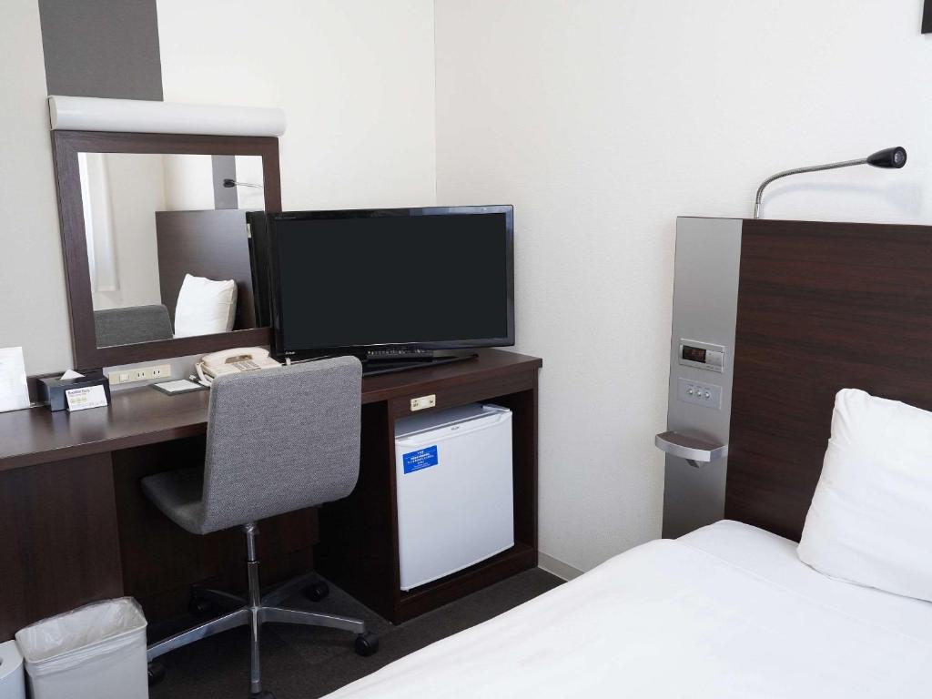 a hotel room with a desk with a television and a bed at Comfort Hotel Tokyo Kanda in Tokyo
