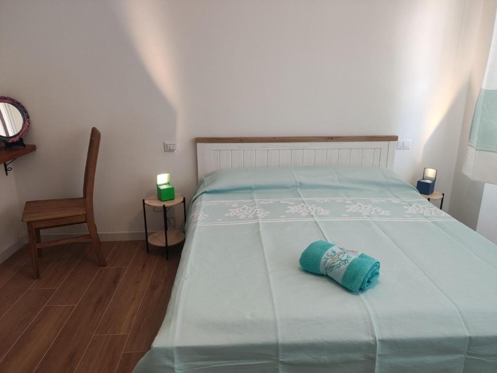 a bedroom with a bed with a blue blanket and a chair at Holiday Rooms in Santa Teresa in Santa Teresa Gallura