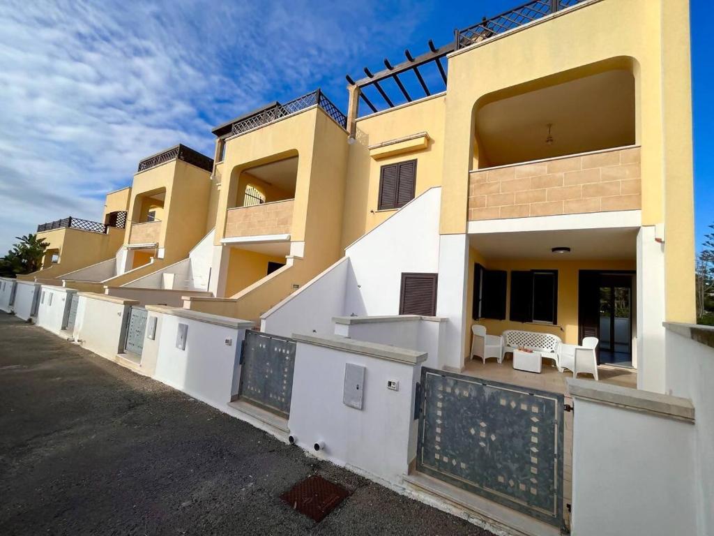 een gebouw met een hek ervoor bij Yellow Beachfront house 60 m by Salento Prime in Marina di Pescoluse