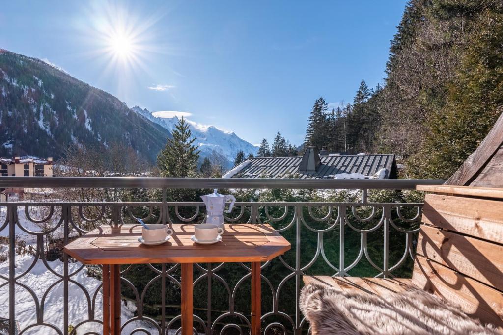 une table sur un balcon avec vue sur les montagnes dans l'établissement Le Cristal MT10 - Central Apartment - Close to ski lift - FreeParking, à Chamonix-Mont-Blanc