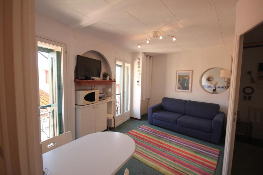 un salon avec un canapé bleu et une télévision dans l'établissement Treille 3 3ème étage, à Collioure