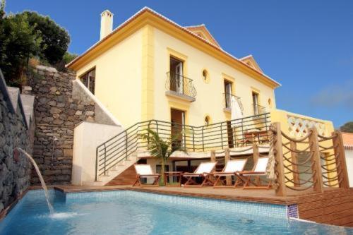 a house with a swimming pool in front of a house at Colina Da Faja in Fajã da Ovelha