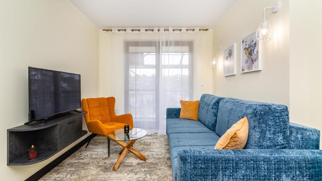 a living room with a blue couch and a tv at Apartament Widok Krynica Morska z widokiem na morze in Krynica Morska