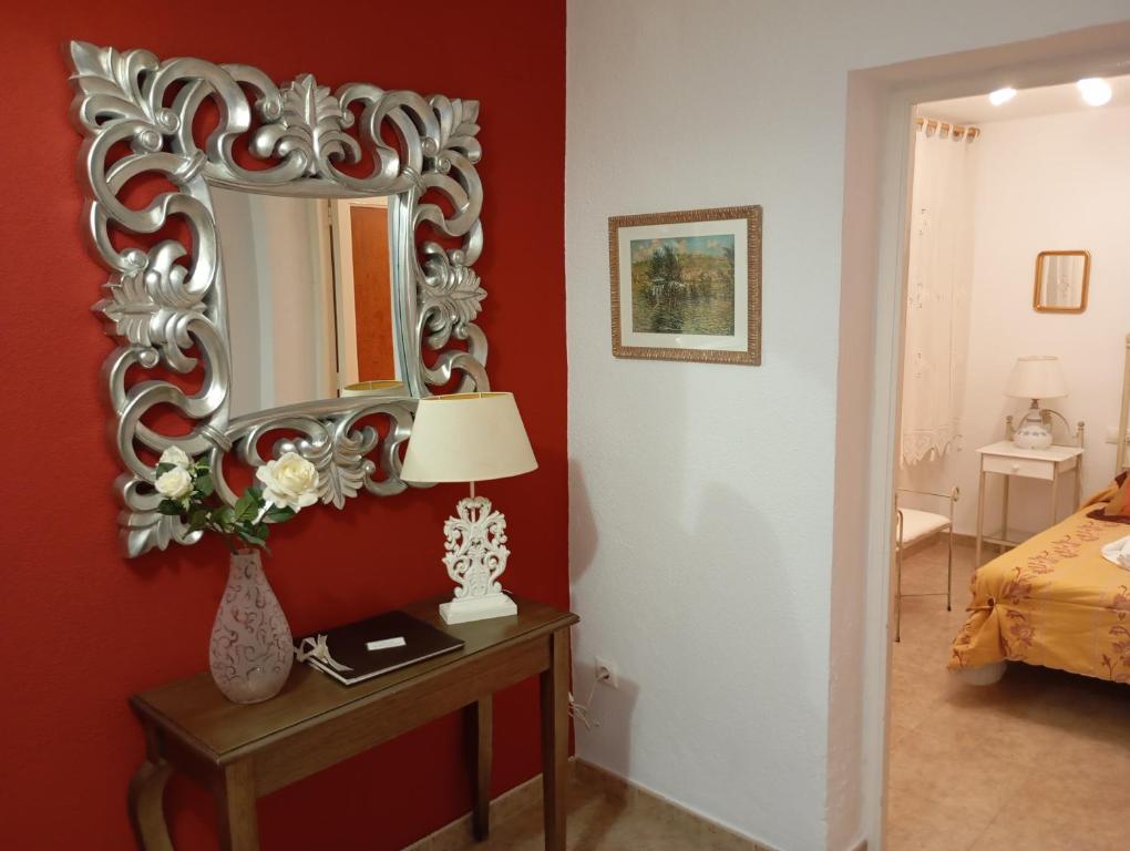 einen Spiegel an einer roten Wand im Schlafzimmer in der Unterkunft Cuencaloft el patio de Pipo in Cuenca