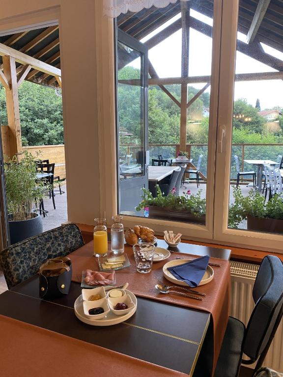 a table with plates of food on it in front of a window at Maison Capdet in Fresse-sur-Moselle