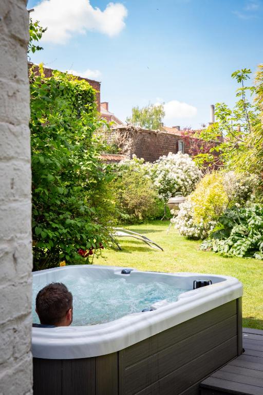 un homme dans un bain à remous dans une cour dans l'établissement Maison du jardin botanique 7 min centre et Gare, à Tourcoing