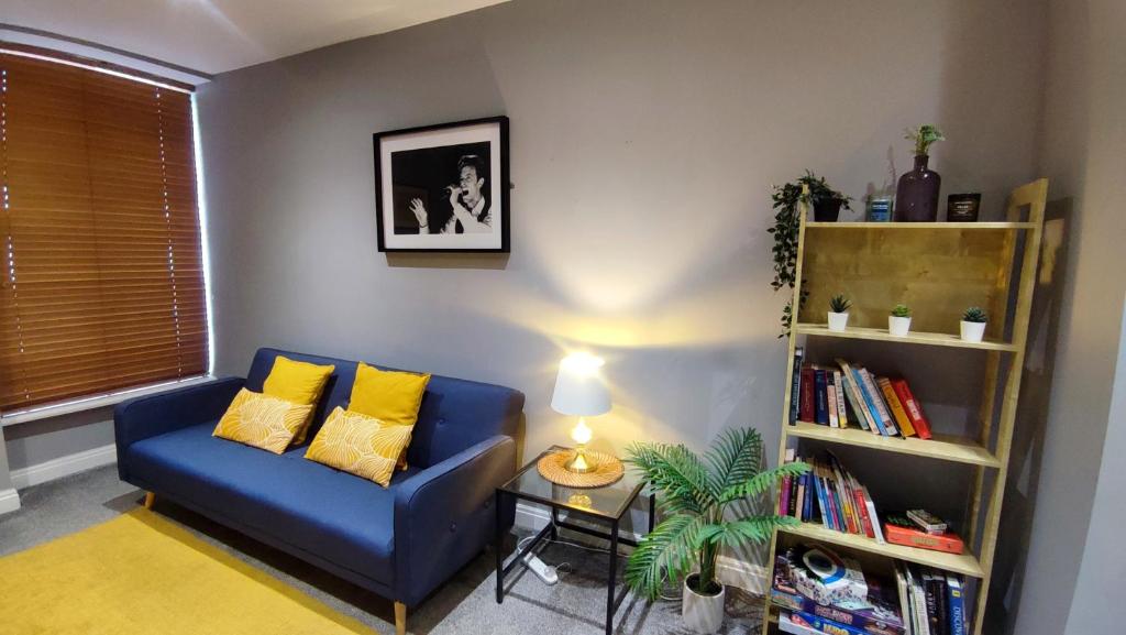 a living room with a blue couch and a book shelf at West Kirby Apartment in West Kirby