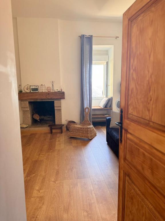 un salon avec une cheminée et une porte en bois dans l'établissement Location atypique village olmeto, à Olmeto