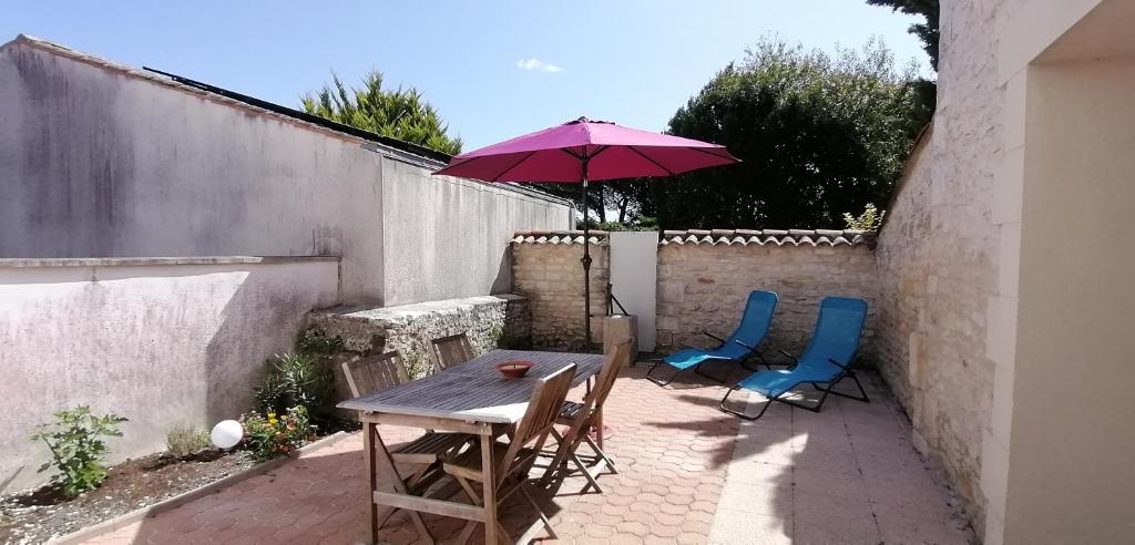 a table and chairs with an umbrella on a patio at Les Roses Trémières - A 1km de la gare garage in Saujon