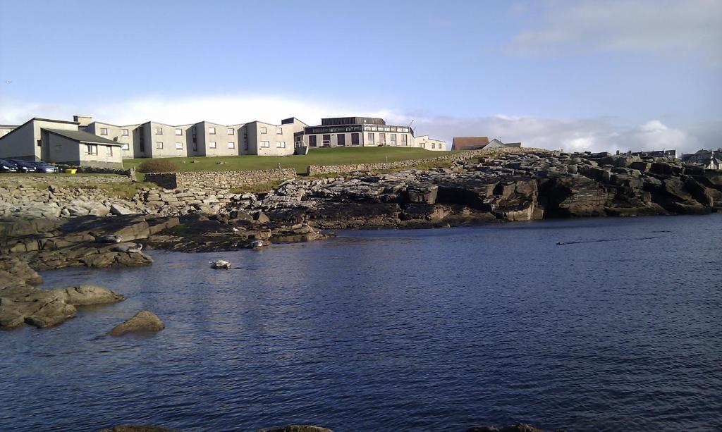 a large body of water with buildings on a cliff at The Lerwick Hotel in Lerwick