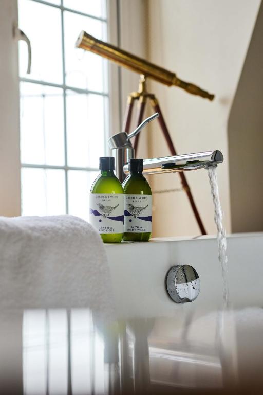 two bottles of detergent sitting on a bathroom sink at Drakes Hotel in Brighton & Hove