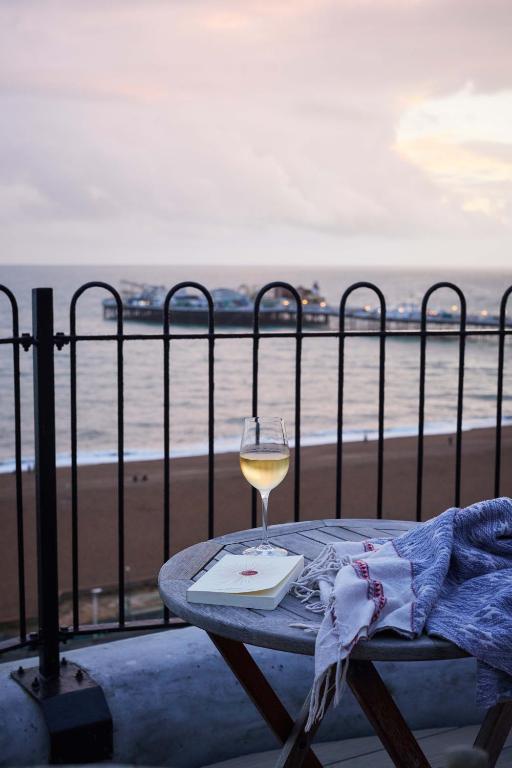 a glass of wine sitting on a table next to the beach at Drakes Hotel in Brighton & Hove