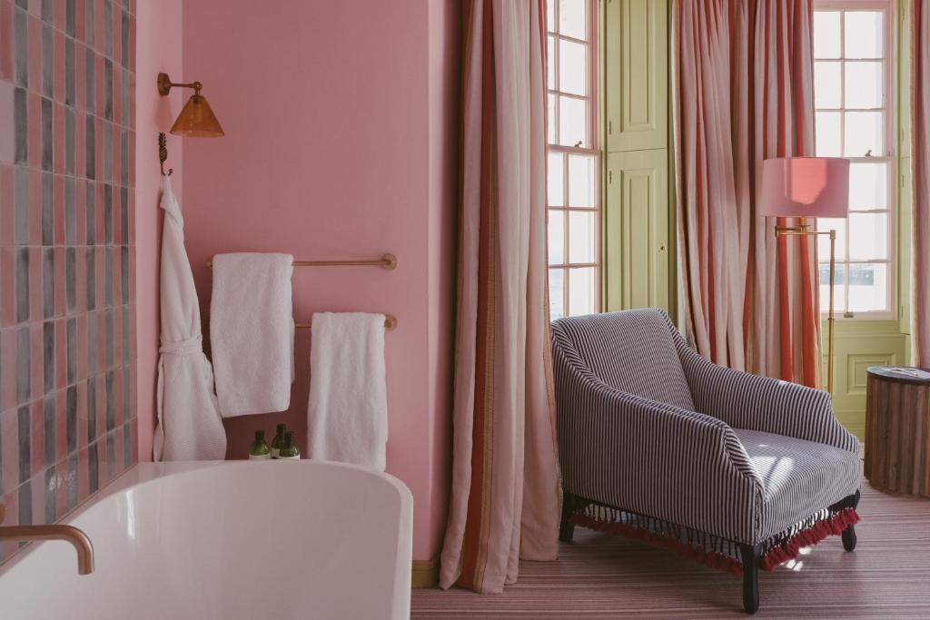 a pink bathroom with a chair and a tub at Drakes Hotel in Brighton & Hove